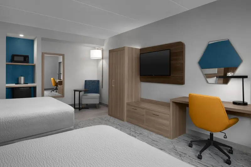 Une chambre d'hôtel moderne avec deux lits et un espace de travail.