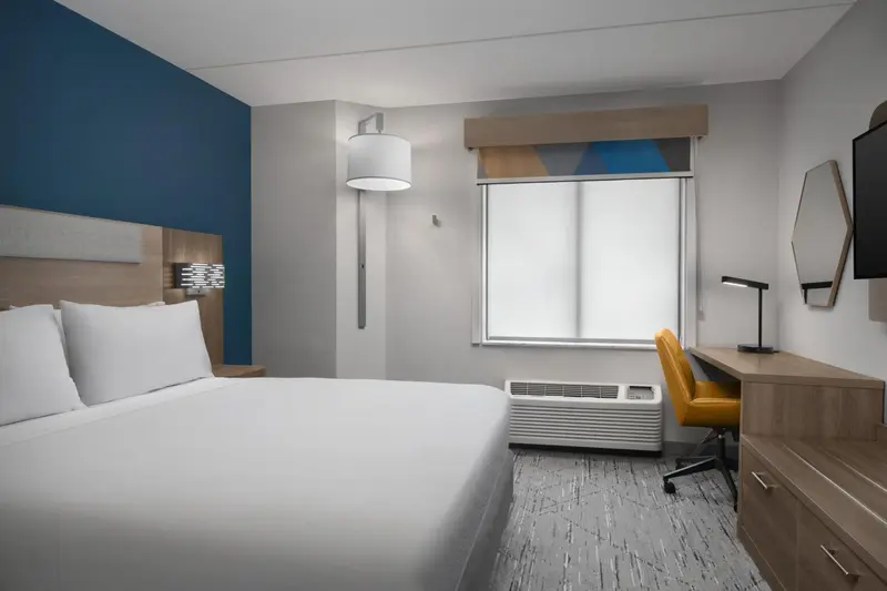 Une chambre d'hôtel lumineuse avec un lit blanc et un bureau.