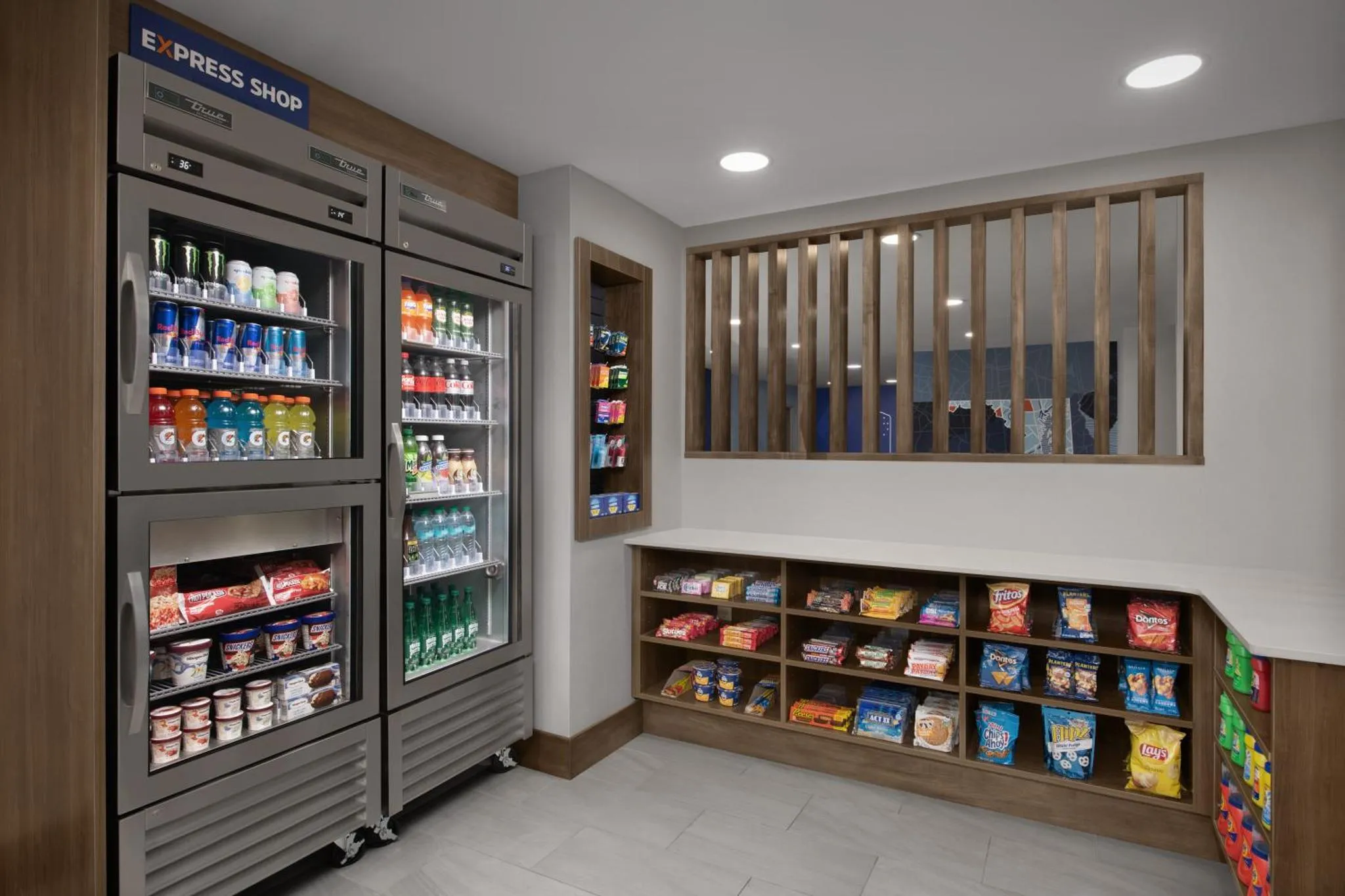 Présentoir réfrigéré rempli de boissons et de collations, avec des étagères de snacks à proximité.