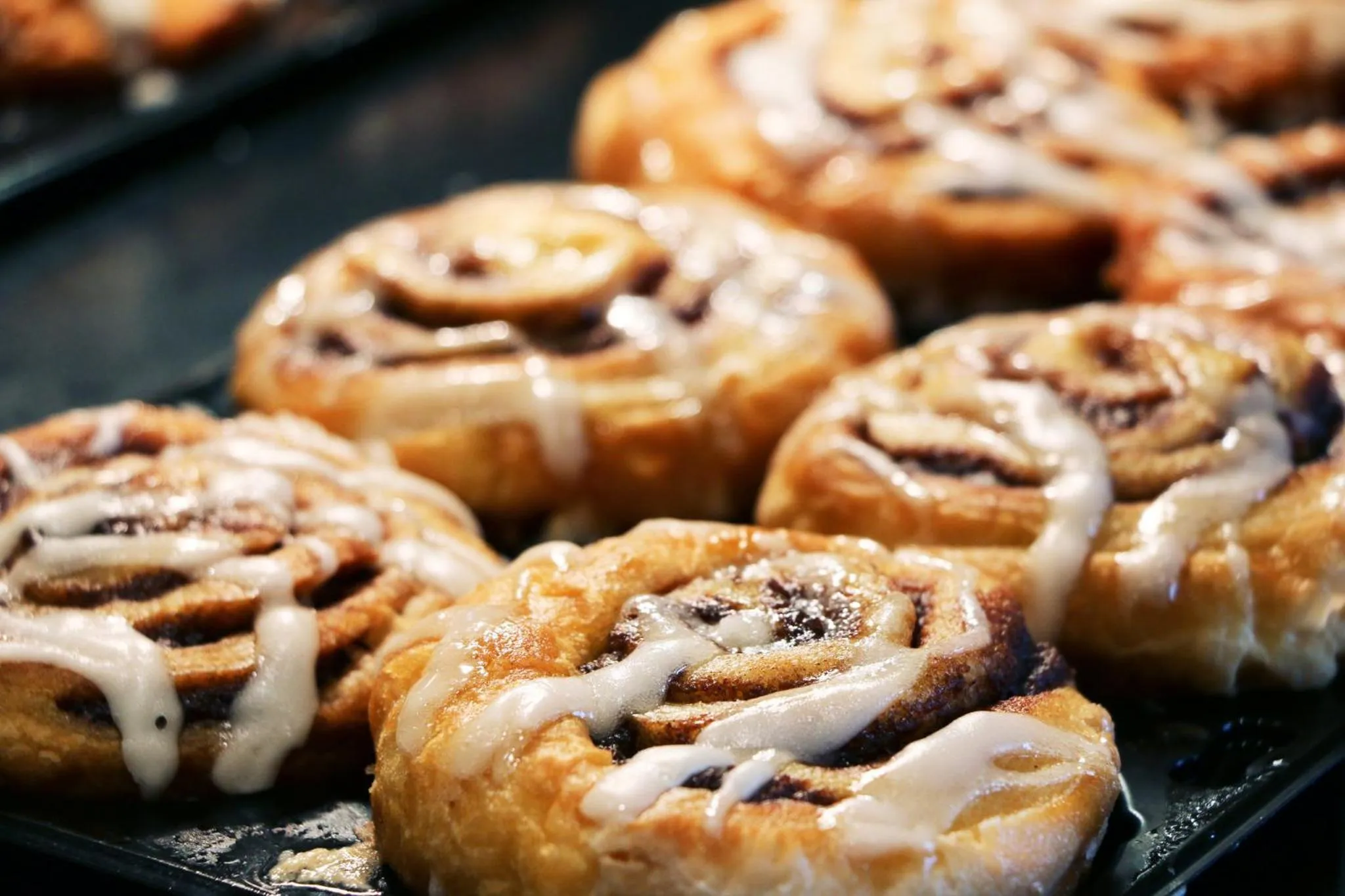 Des viennoiseries au caramel et au glaçage sont alignées sur une plaque de cuisson.