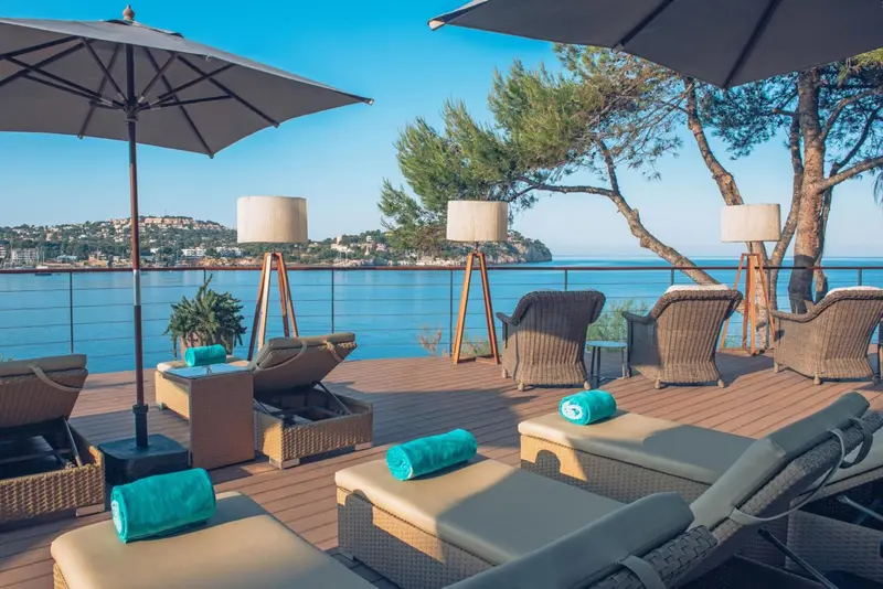 Terrasse aménagée avec des chaises longues et des lampadaires en bord de mer.