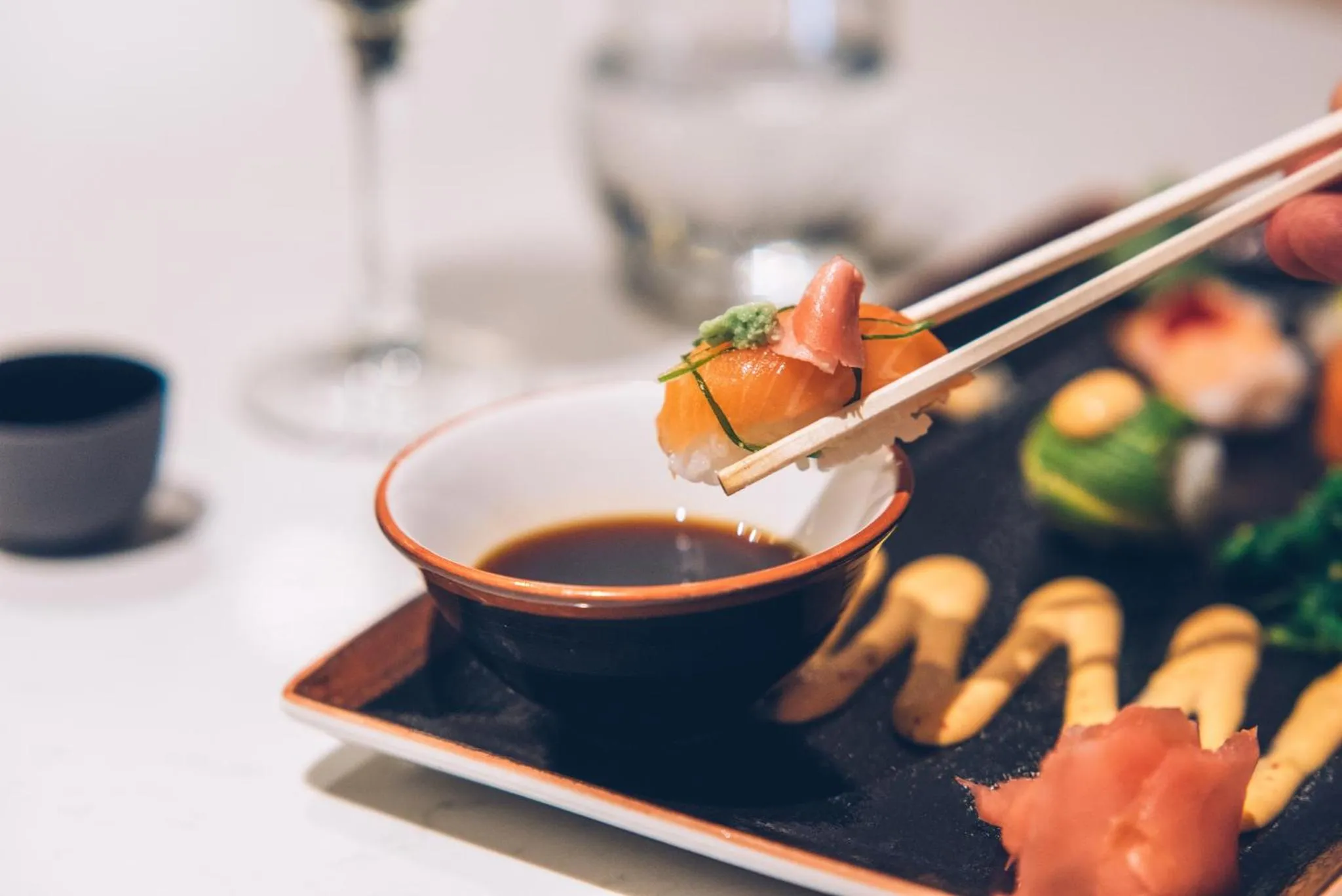 Un sushi est saisi avec des baguettes au-dessus d'une sauce soja.