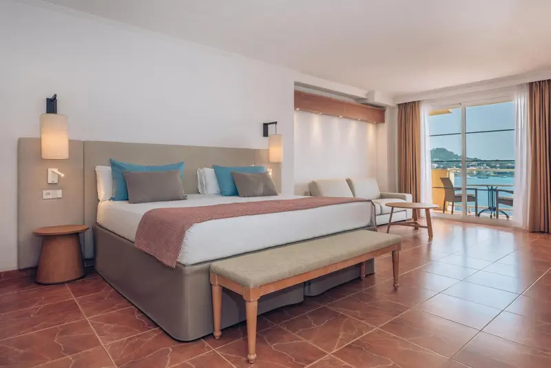 Une chambre lumineuse avec un grand lit et un accès à un balcon.