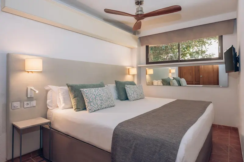 Une chambre lumineuse avec un grand lit et des coussins décoratifs.