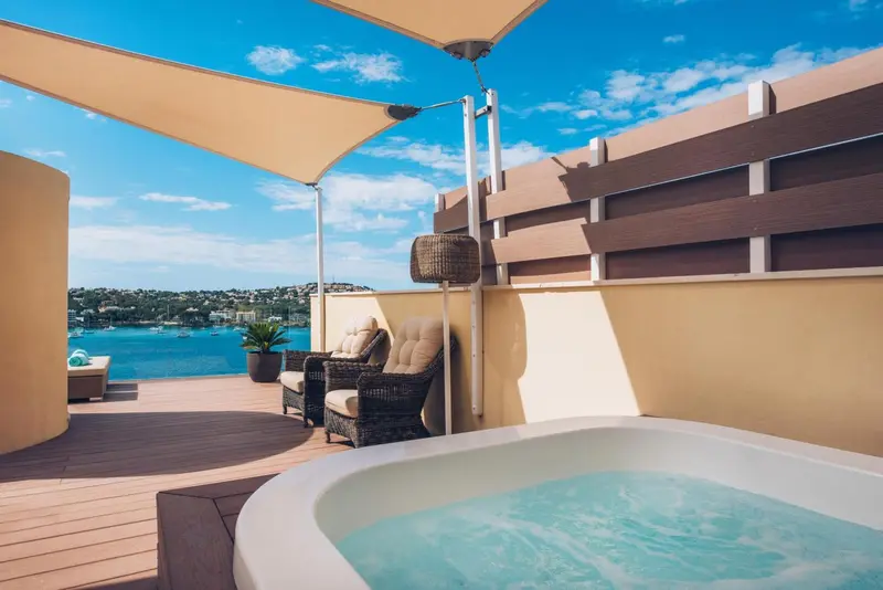 Terrasse avec jacuzzi et mobilier de jardin offrant une vue sur la mer.