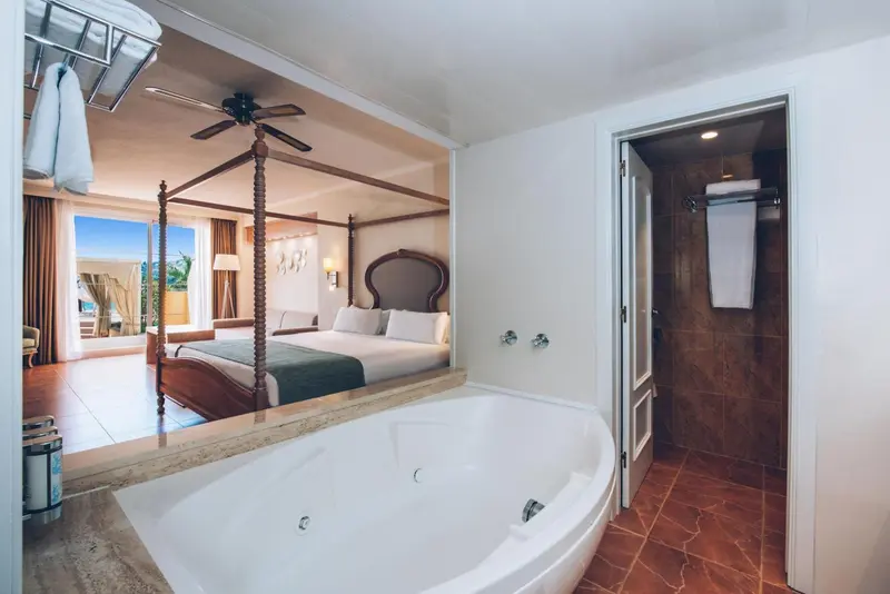 Une chambre spacieuse avec un lit à baldaquin et une baignoire îlot.