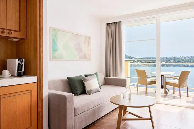 Un espace de séjour lumineux avec canapé et accès à une terrasse vue mer.