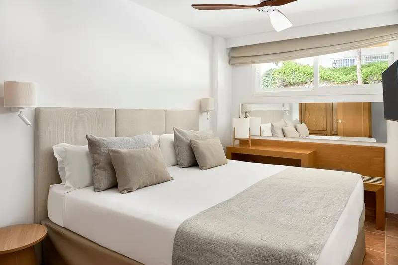 Une chambre lumineuse avec un grand lit et des coussins décoratifs.