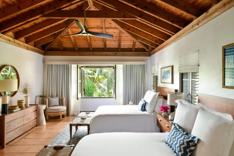 Une chambre lumineuse avec deux lits simples et une décoration tropicale.