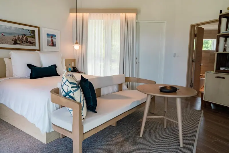 Une chambre lumineuse avec un lit fait et un coin salon.
