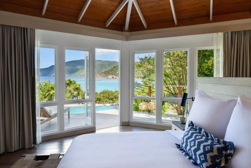 Une chambre lumineuse avec vue sur la mer et une piscine.