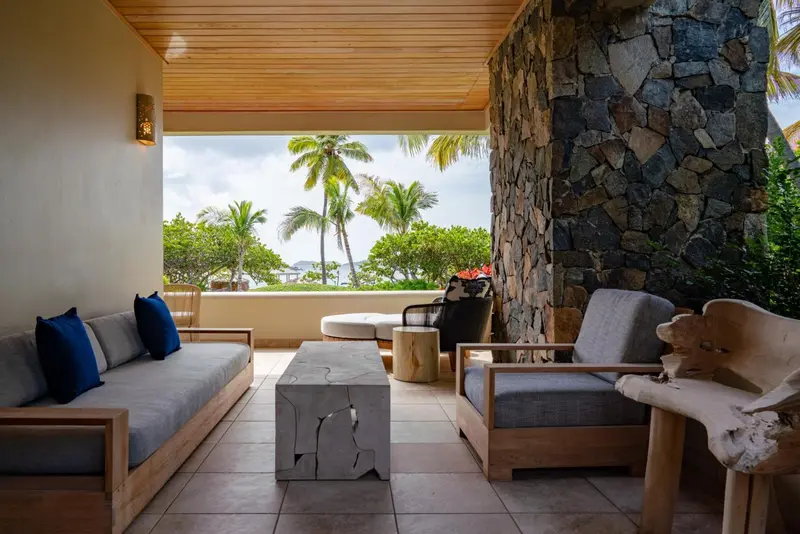 Espace de détente extérieur avec canapés et vue sur la végétation tropicale.