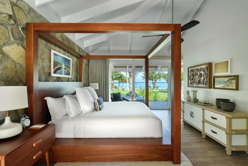 Une chambre lumineuse avec un grand lit à baldaquin donnant sur une vue sur la mer.