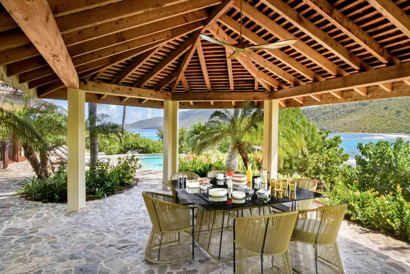 Une table dressée pour le petit-déjeuner se trouve sous une pergola en bois.