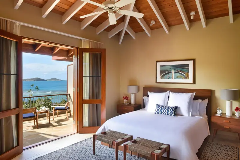 Une chambre lumineuse s'ouvre sur une vue mer depuis de grandes portes-fenêtres.