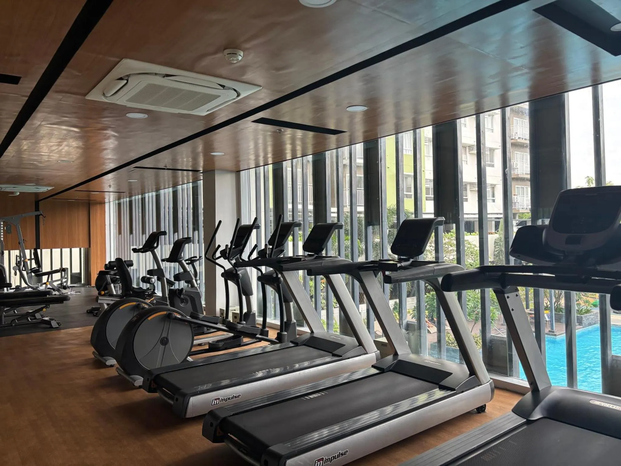 Une salle de sport lumineuse avec plusieurs tapis de course et vélos d'appartement.