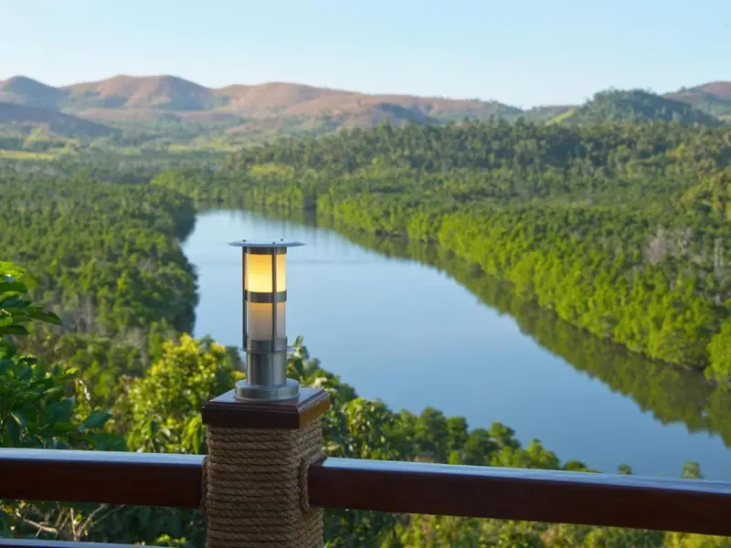 Une lanterne illumine une terrasse surplombant une rivière et des collines verdoyantes.