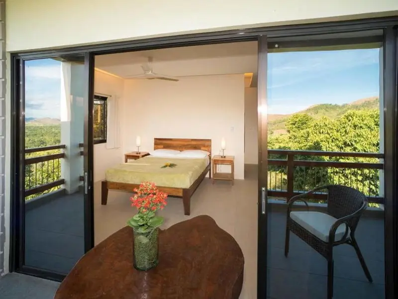 Une chambre lumineuse s'ouvre sur une terrasse avec vue sur les collines.