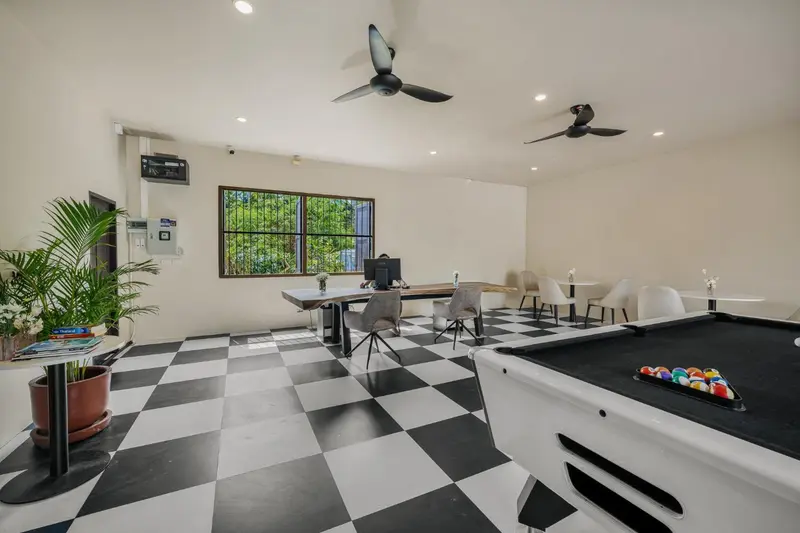 Espace de détente avec table de jeu et billard sur un sol à carreaux.