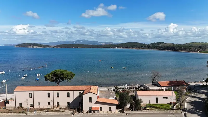 Vue aérienne d'une côte rocheuse avec des bâtiments et la mer au loin.
