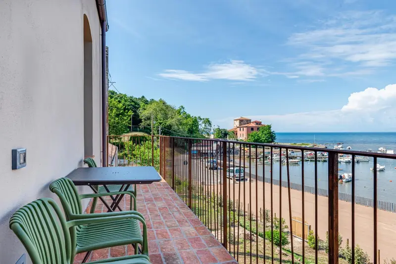 Terrasse avec mobilier d'extérieur donnant sur la mer et un port.