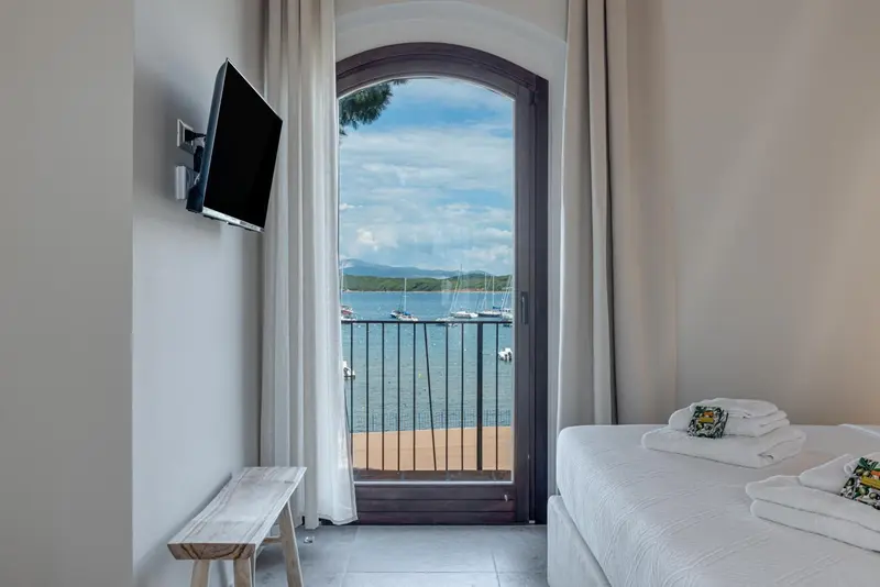 Une chambre lumineuse s'ouvre sur une vue mer par une arche.
