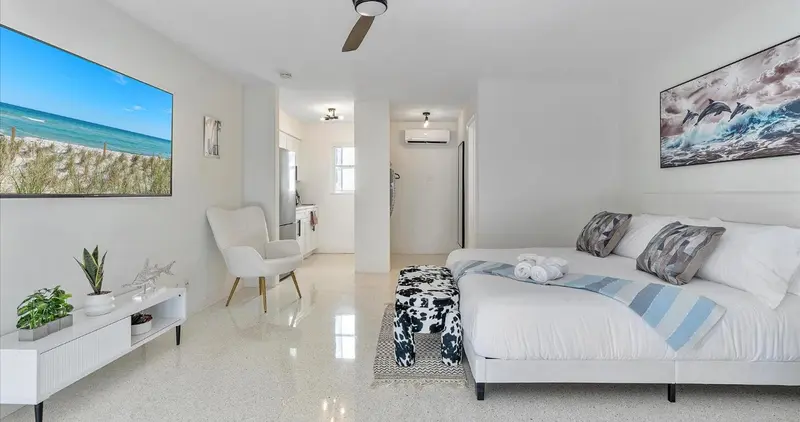 Une chambre lumineuse avec un grand lit et un téléviseur mural.