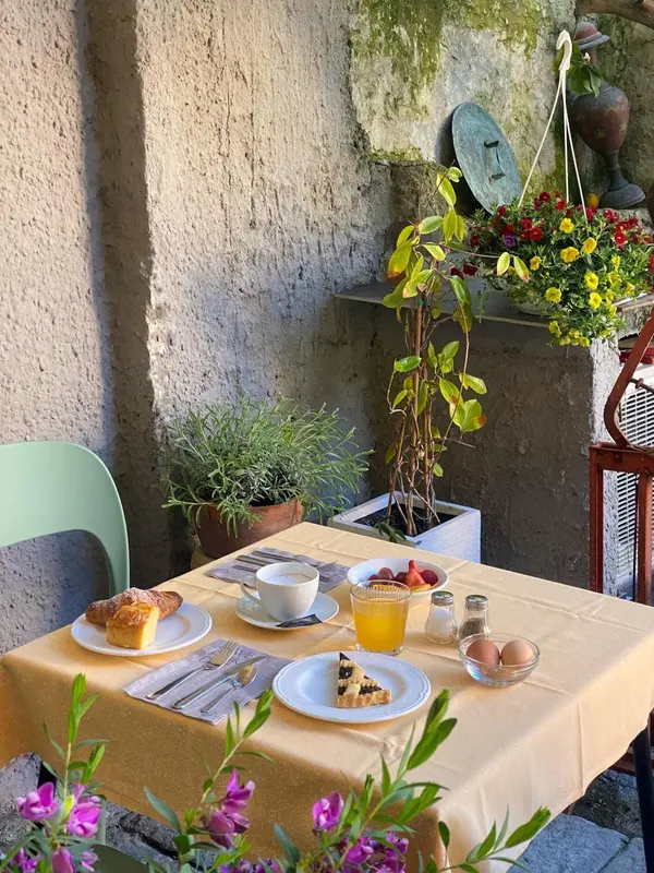 Une table jaune est dressée avec une viennoiserie, des fruits et une boisson.