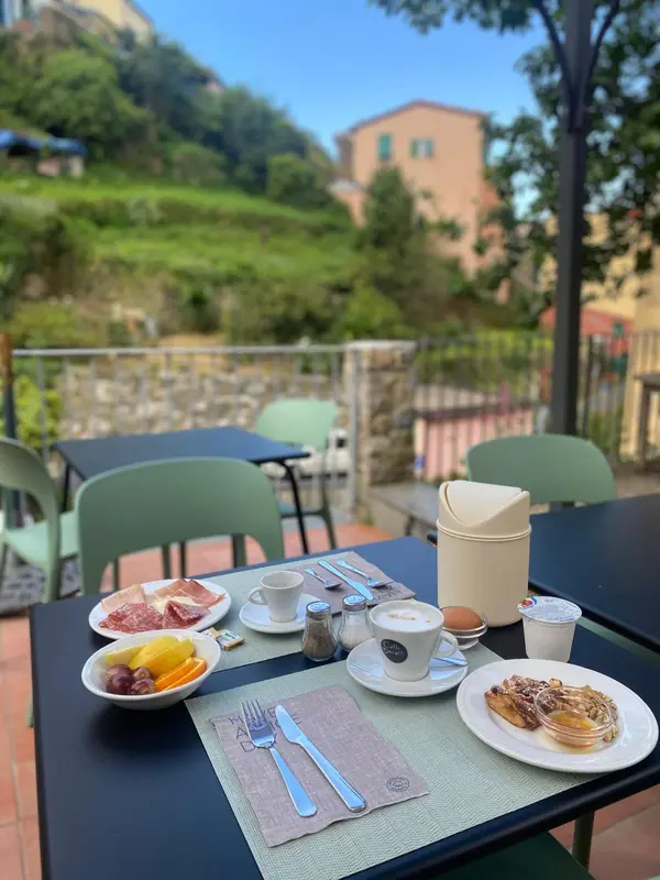 Une table est dressée pour le petit-déjeuner avec des viennoiseries, des fruits et des boissons.