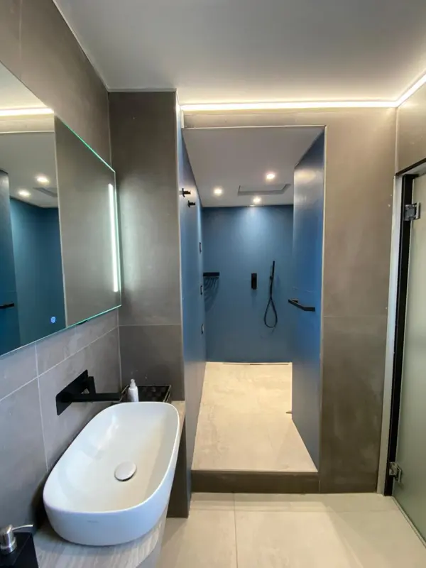 Une baignoire blanche se trouve devant une douche à l'italienne dans une salle de bain moderne.