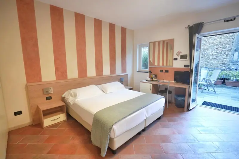 Une chambre lumineuse avec un lit double et un accès à une terrasse.