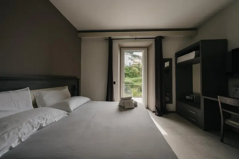 Une chambre avec un lit double et une fenêtre ouverte sur un paysage verdoyant.