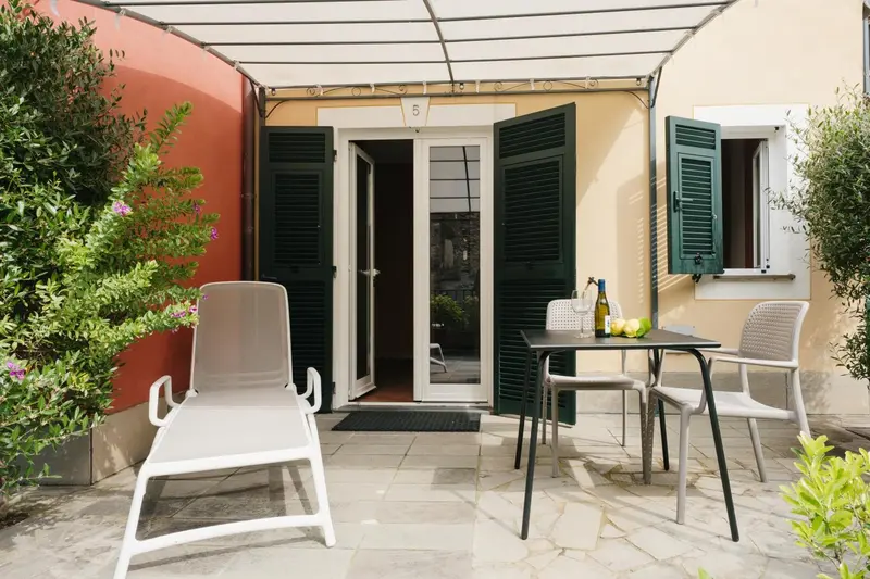 Terrasse carrelée avec mobilier d'extérieur et accès à une porte-fenêtre.