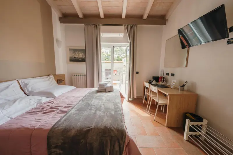 Une chambre lumineuse avec un lit double et un accès à un balcon.