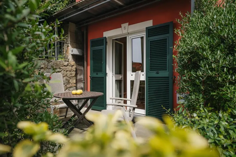 Une petite terrasse ombragée avec une table et des chaises en fer forgé.