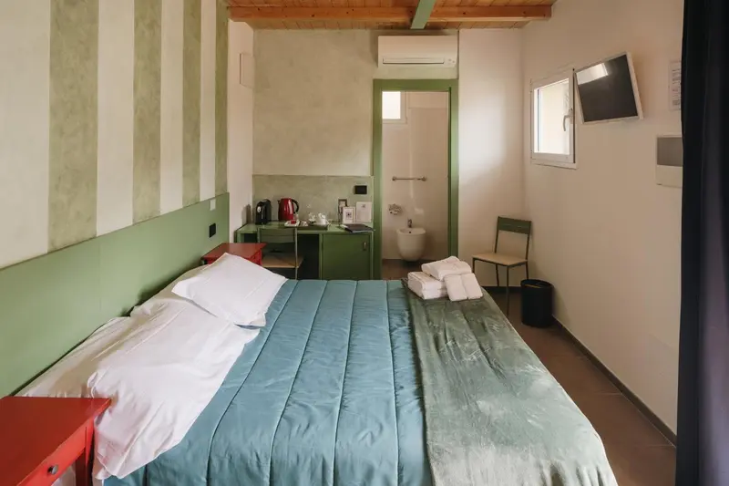 Une chambre lumineuse avec un lit fait et un bureau.