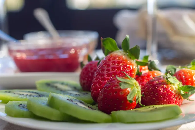 Assiette de fruits frais avec des fraises, du kiwi et de la confiture.