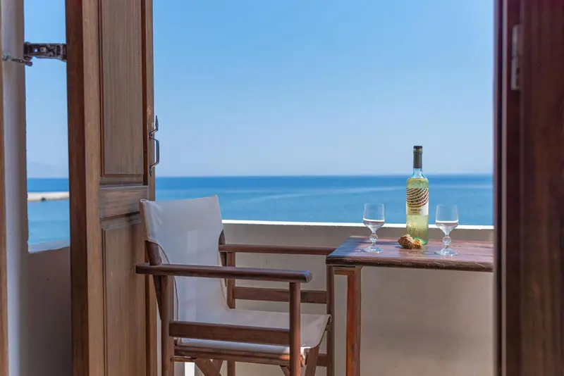 Une table et une chaise en bois offrent une vue sur la mer depuis un balcon.
