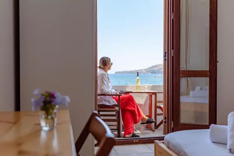 Une personne assise sur une terrasse ensoleillée avec vue sur la mer.