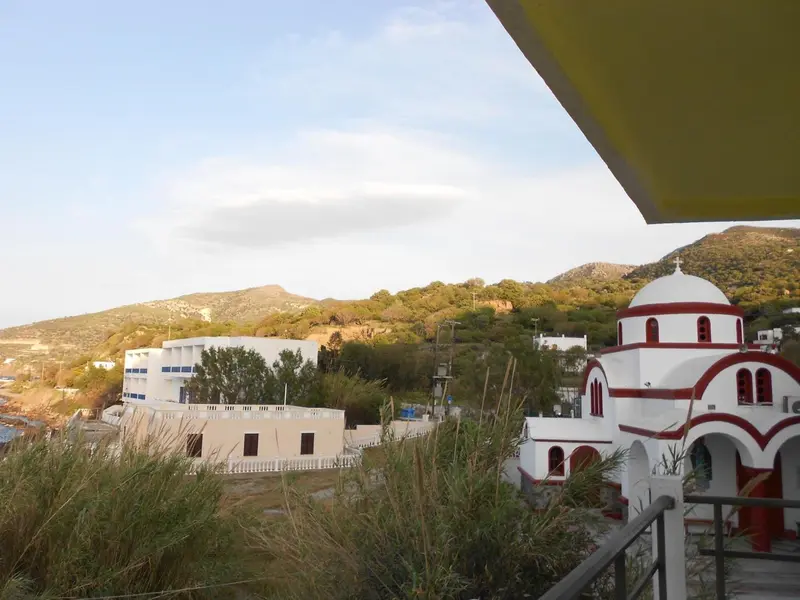 Vue sur un paysage montagneux et un village côtier avec une église blanche.