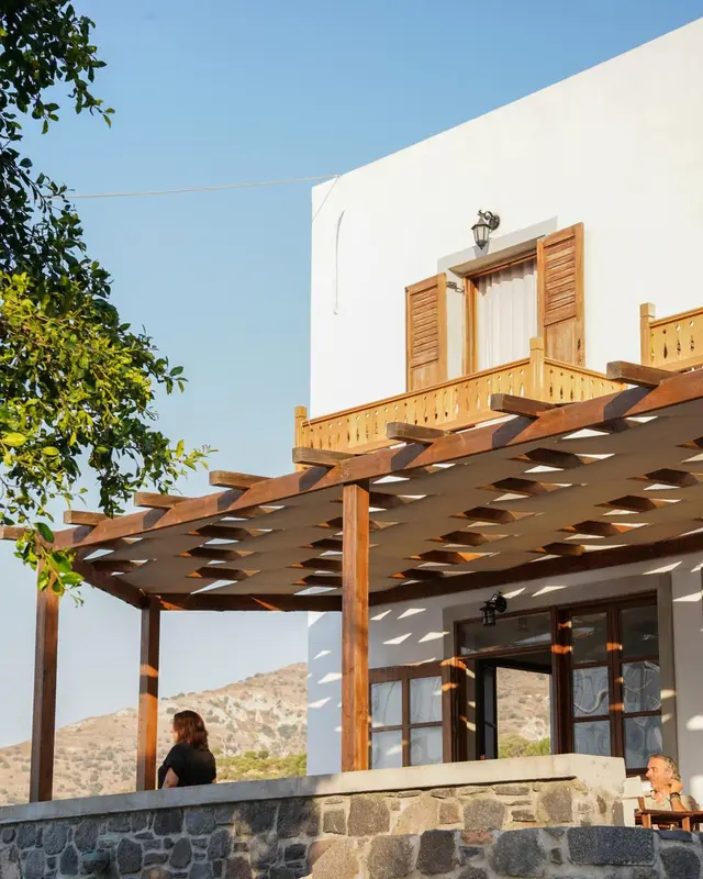 Pergola ombrageant une terrasse devant un bâtiment blanc.