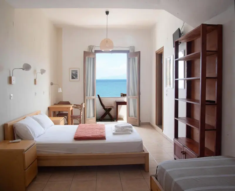 Chambre lumineuse avec un lit simple et un bureau donnant sur la mer.