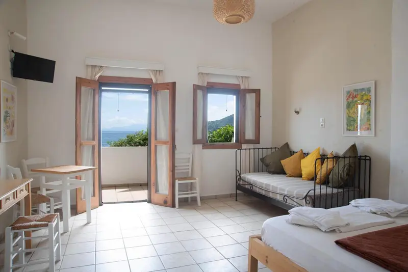 Une pièce lumineuse avec un lit, un coin repas et une vue sur la mer.