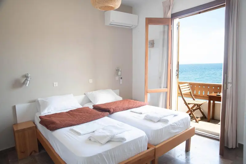Une chambre lumineuse avec un lit double et un accès à un balcon avec vue sur la mer.