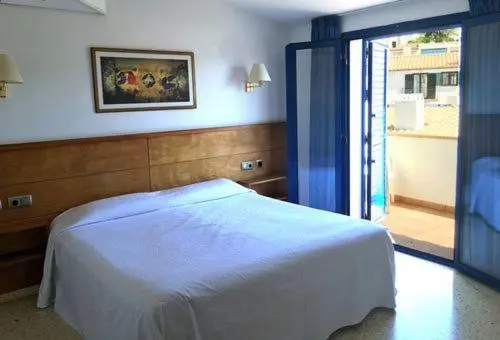 Une chambre lumineuse avec un lit recouvert d'une couverture blanche et un accès à une terrasse.