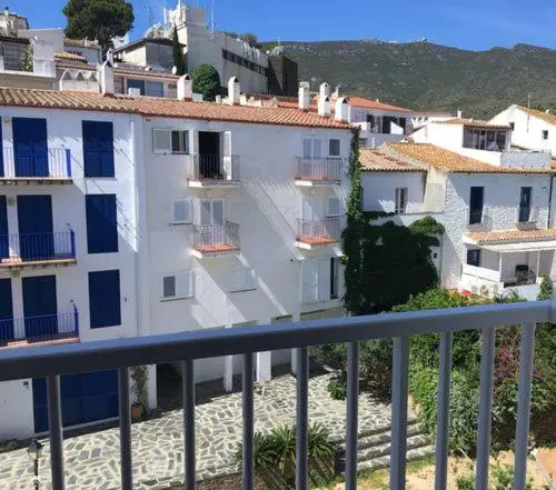 Vue d'ensemble d'un village blanc avec des bâtiments aux toits rouges et des balcons fleuris.