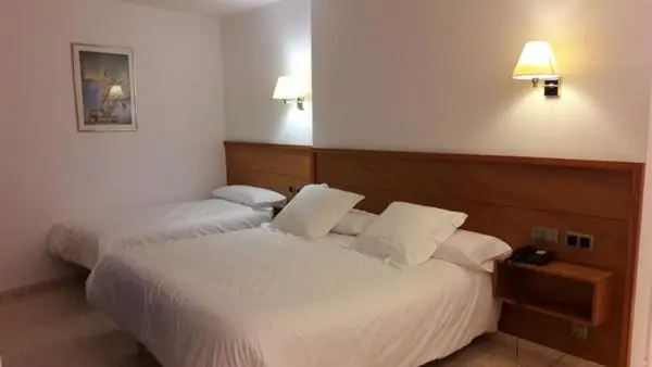 Une chambre d'hôtel avec deux lits simples et des tables de chevet.