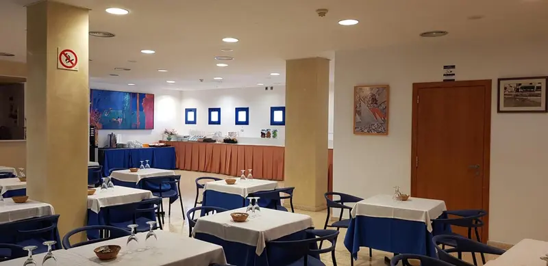 Une salle lumineuse avec des tables dressées pour le repas.