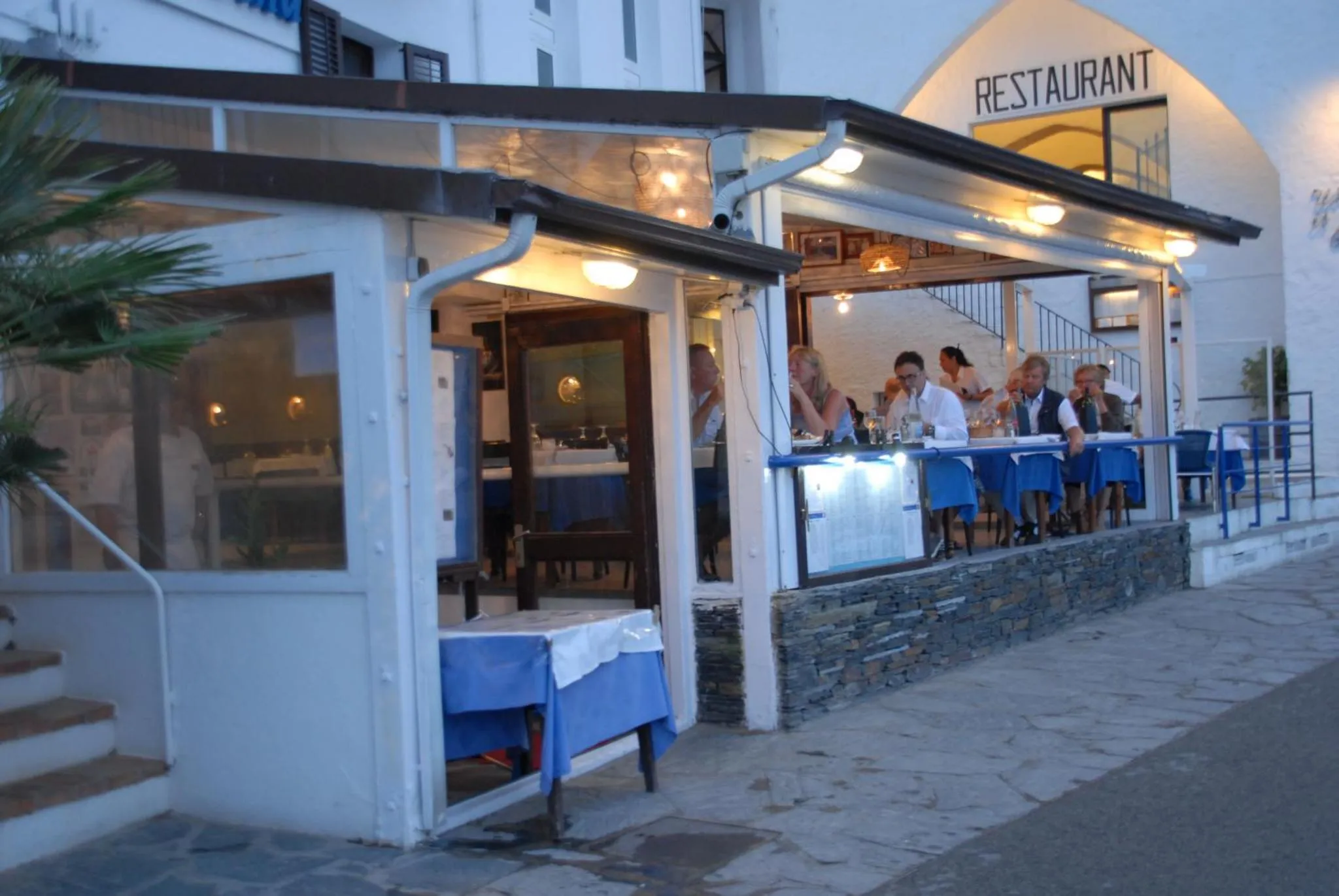 Une terrasse de restaurant avec des clients attablés en soirée.
