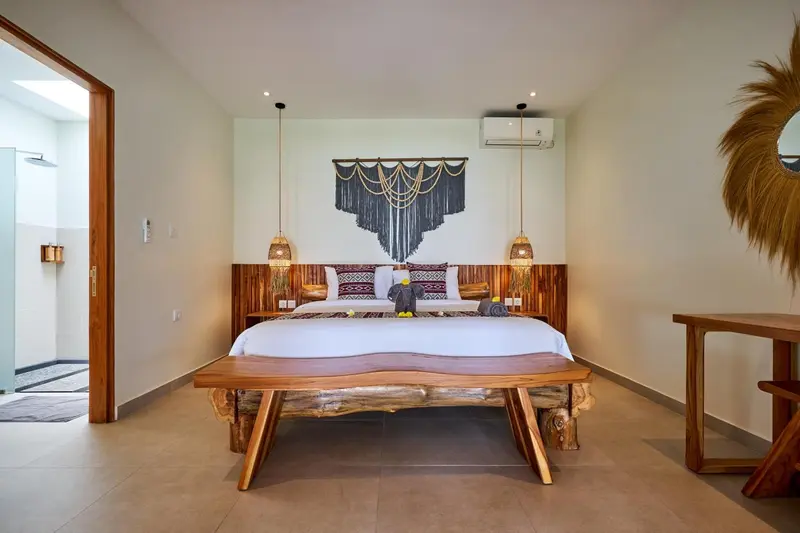 Une chambre lumineuse avec un grand lit et une décoration murale en fibres naturelles.